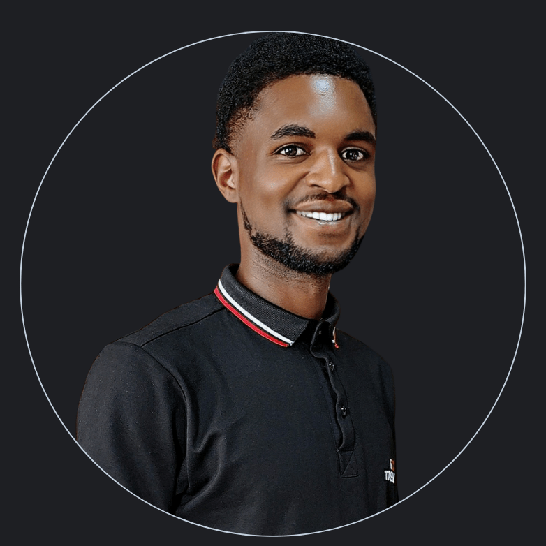 A man with short curly hair, a beard, and a bright smile is pictured against a dark background. He is wearing a black collared shirt with a white and red-trimmed neckline. The image, framed within a circular border, tells you all about his cheerful demeanor.